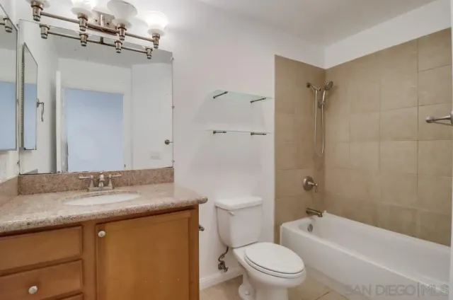a bathroom with a granite countertop sink a toilet a mirror and shower