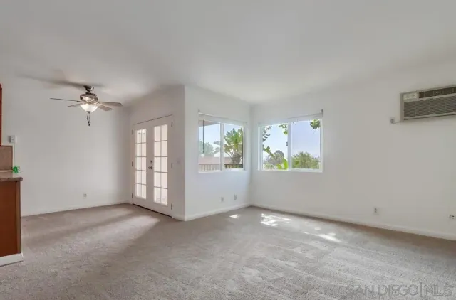 an empty room with windows and chandelier fan