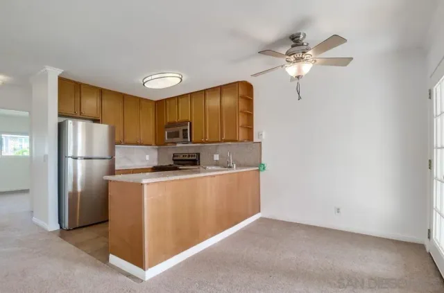 a kitchen with stainless steel appliances a refrigerator and a chandelier