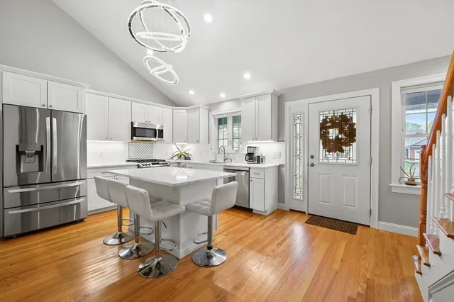 a kitchen with stainless steel appliances granite countertop a refrigerator a stove a sink dishwasher and white countertops with wooden floor