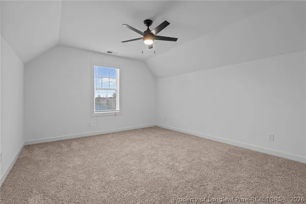 an empty room with ceiling fan and windows