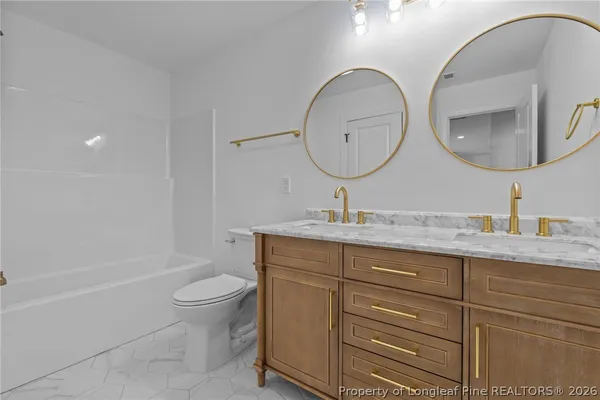 a bathroom with a granite countertop toilet a sink and a mirror