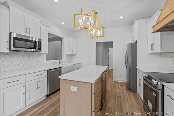 a kitchen with cabinets a sink stainless steel appliances and wooden floor