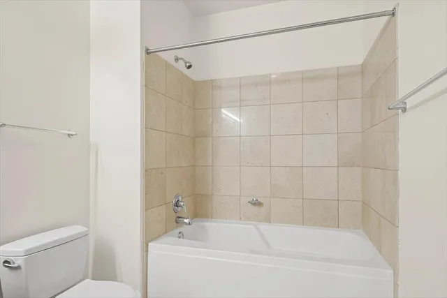 a white bath tub sitting next to a white toilet and a shower
