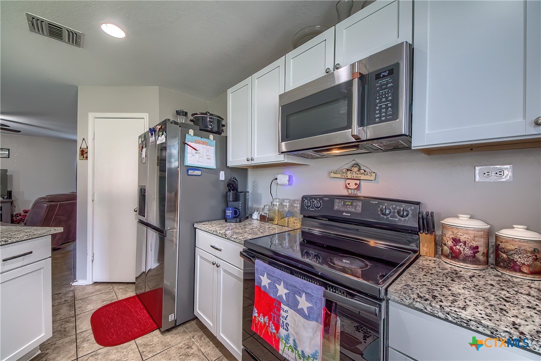 5709 Ping Way Schertz, TX 78108 - Photo 10 of 28 a kitchen with stainless steel appliances granite countertop a stove refrigerator and microwave