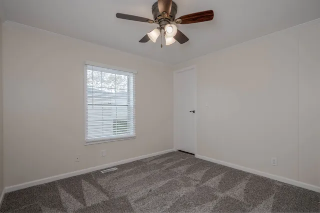 an empty room with a window and a fan