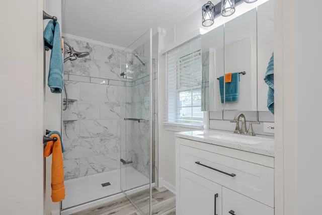 a bathroom with a shower sink vanity and mirror