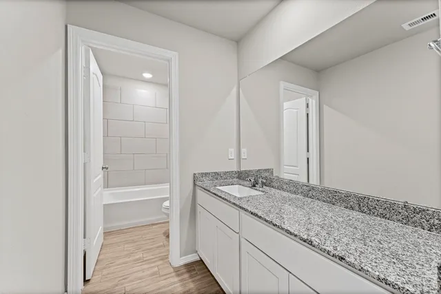 a bathroom with a granite countertop sink and a mirror