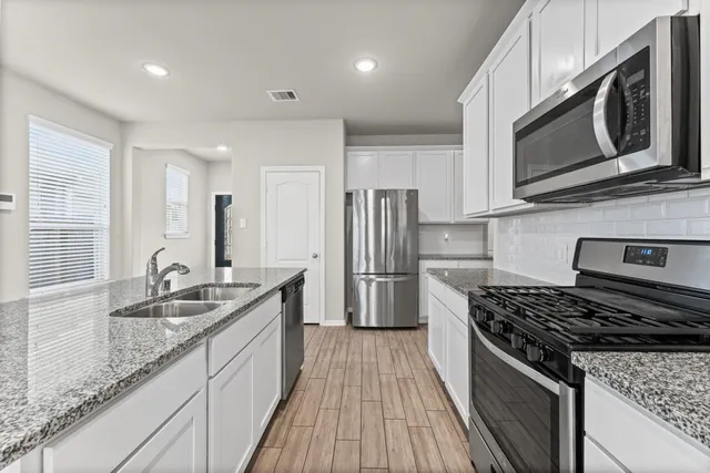 a kitchen with stainless steel appliances granite countertop a sink stove and refrigerator