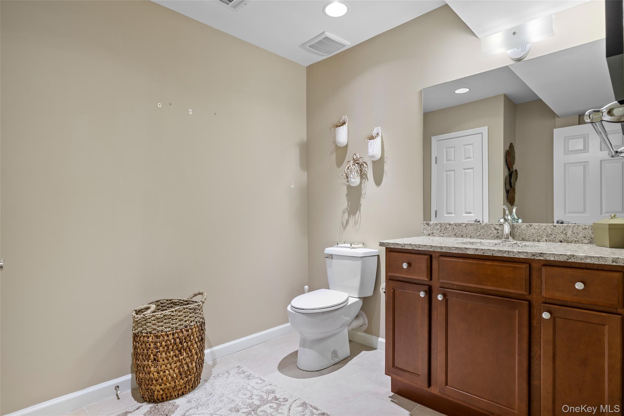 56 Spring Drive Seaford, NY 11783 - Photo 24 of 42 a bathroom with a granite countertop sink a toilet and a mirror