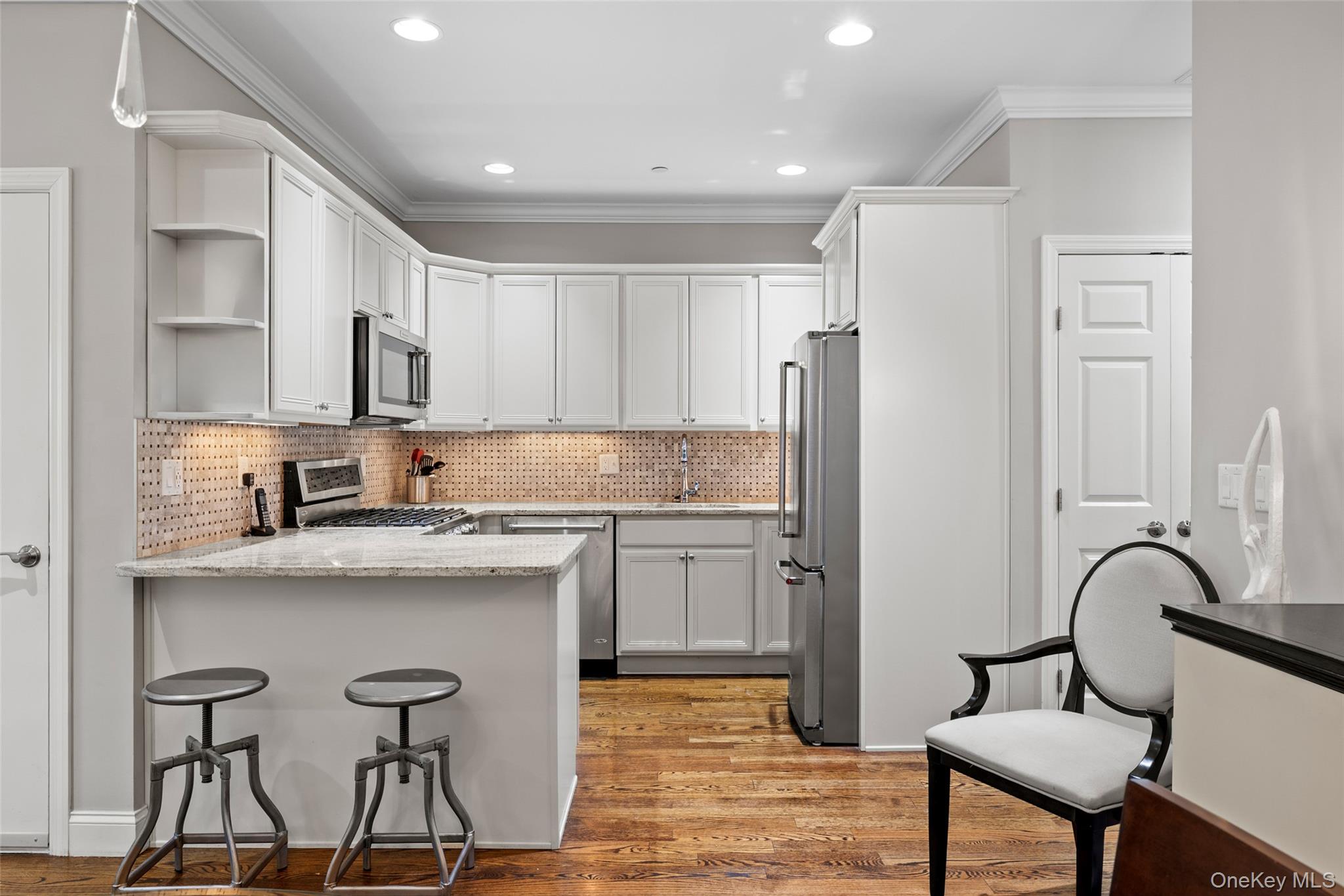 56 Spring Drive Seaford, NY 11783 - Photo 8 of 42 a kitchen with stainless steel appliances granite countertop a white refrigerator a sink a stove and chairs with wooden floor