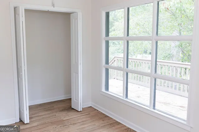 a view of an empty room with wooden floor and a window