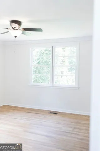a view of an empty room with wooden floor and a window