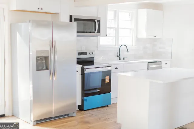 a kitchen with stainless steel appliances a refrigerator sink and microwave