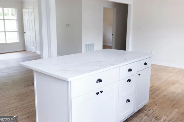 a room with white cabinets and wooden floor