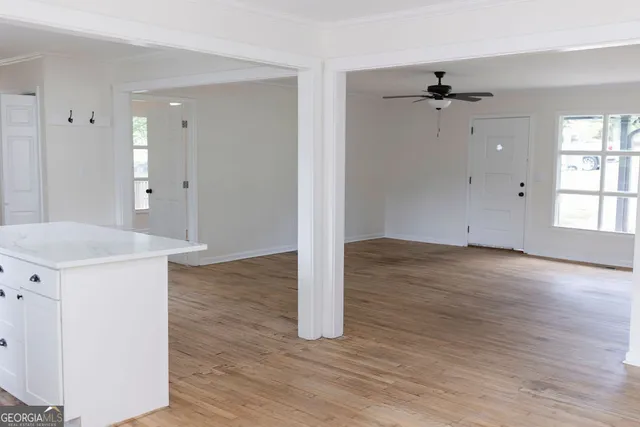 a view of empty room with wooden floor and fan