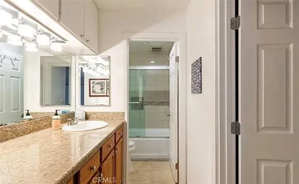 a bathroom with a granite countertop sink two mirror and a shower
