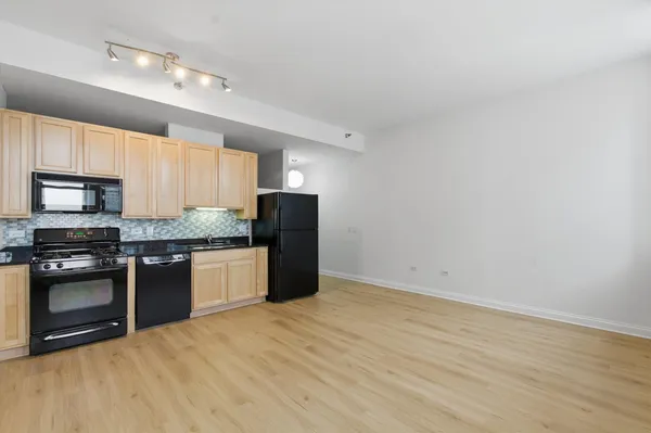 a kitchen with granite countertop a refrigerator and a stove top oven