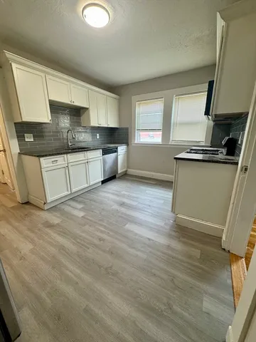 a kitchen with granite countertop a sink cabinets and wooden floor