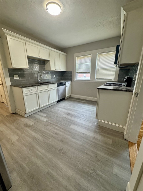 a kitchen with granite countertop a sink cabinets and wooden floor