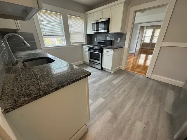 a kitchen with granite countertop a stove a sink and a microwave