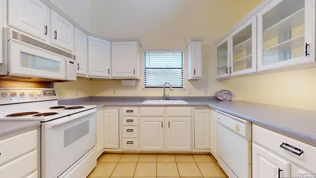 a kitchen with granite countertop white cabinets and white appliances