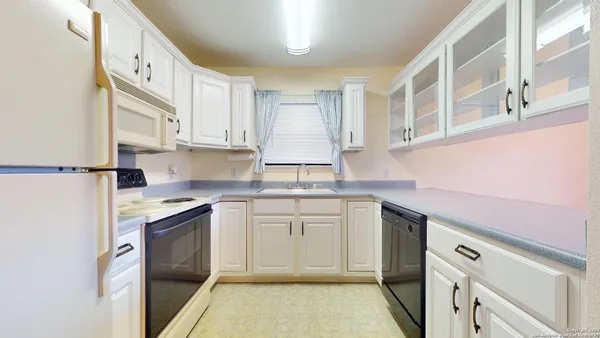 a kitchen with white cabinets and white appliances