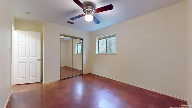an empty room with wooden floor ceiling fan and windows