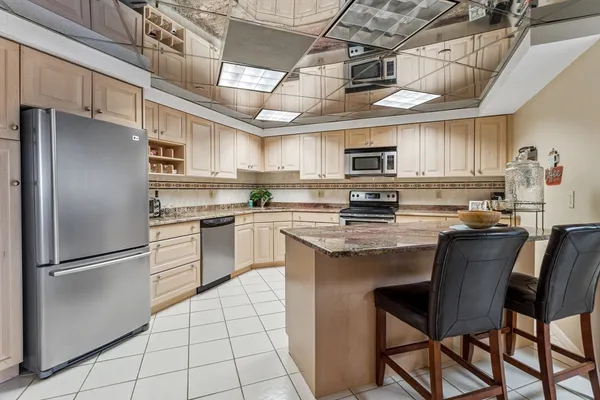a kitchen with stainless steel appliances granite countertop a stove a sink dishwasher a refrigerator and a refrigerator with wooden cabinets