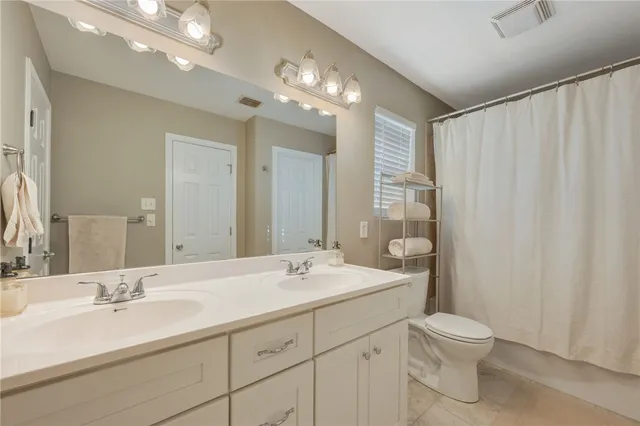 a bathroom with a double vanity sink toilet and a mirror