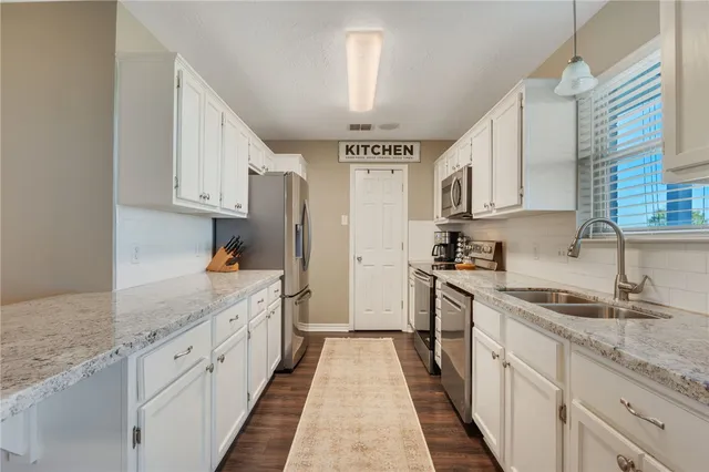 a kitchen with granite countertop a sink stove refrigerator and cabinets