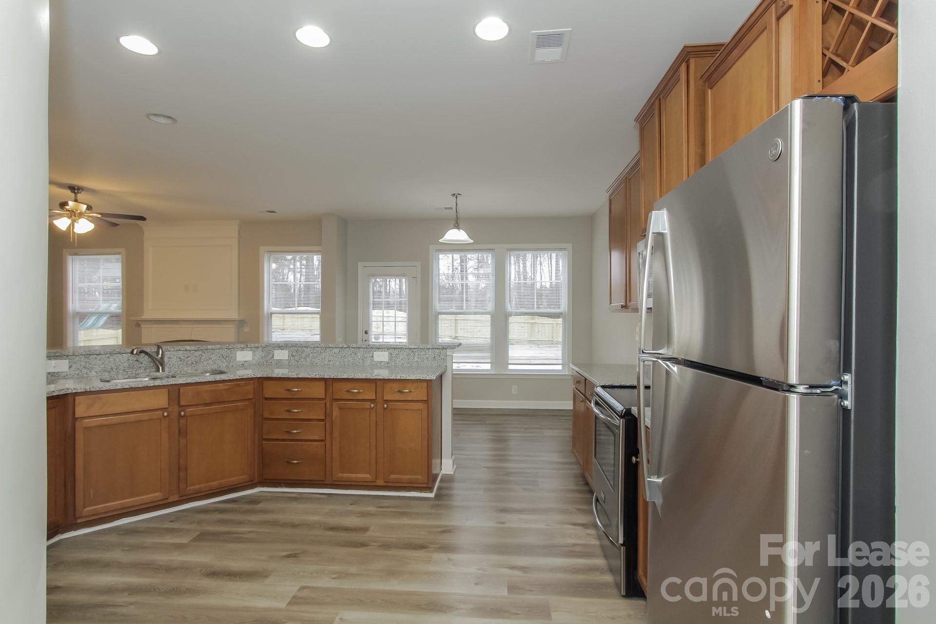 11004 Greenhead View Road Charlotte, NC 28262 - Photo 5 of 17 a large kitchen with a refrigerator a sink dishwasher a stove and white cabinets with wooden floor