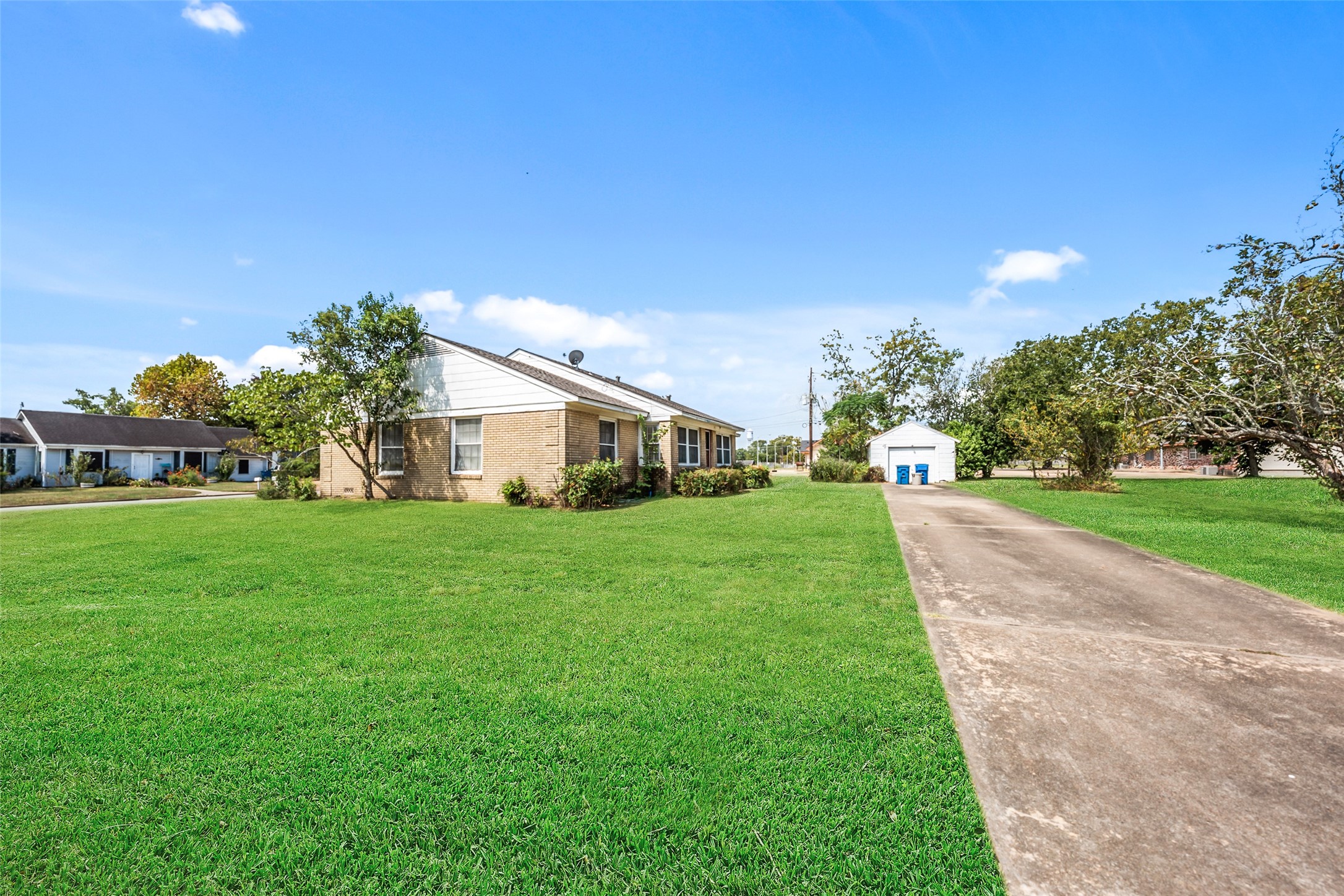 810 Main Street Hempstead, TX 77445 - Photo 9 of 32 Street-level view showcasing the home, expansive front lawn, and long concrete driveway providing ample off-street parking