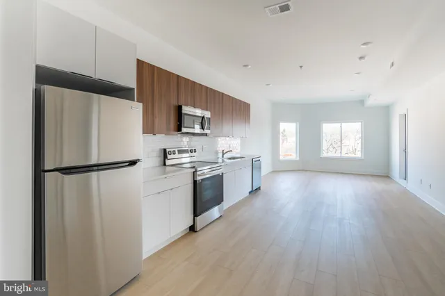 a kitchen with a refrigerator a stove top oven a sink and dishwasher with wooden floor