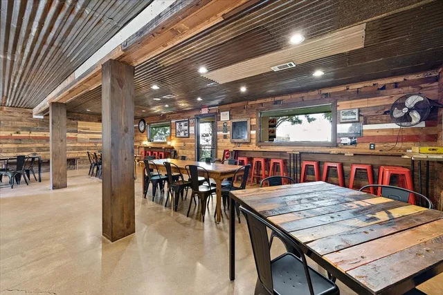 a dining hall with stainless steel appliances granite countertop a sink and a refrigerator