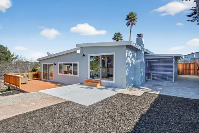 a view of a house with wooden deck and furniture