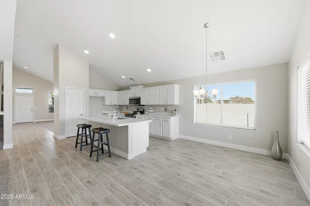 a open kitchen with white cabinets and wooden floor