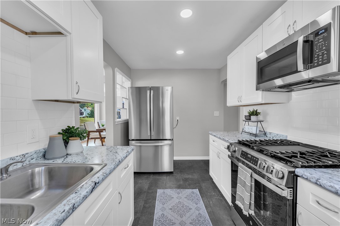 4322 Roadoan Road Brooklyn, OH 44144 - Photo 12 of 27 Kitchen featuring sink, appliances with stainless steel finishes, light stone countertops, and white cabinetry