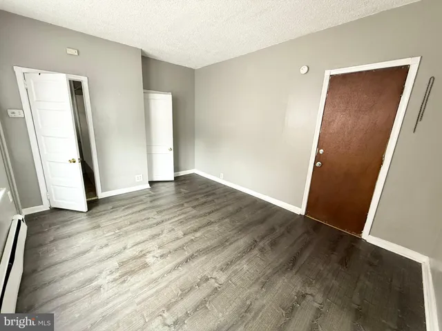 an empty room with wooden floor and entrance