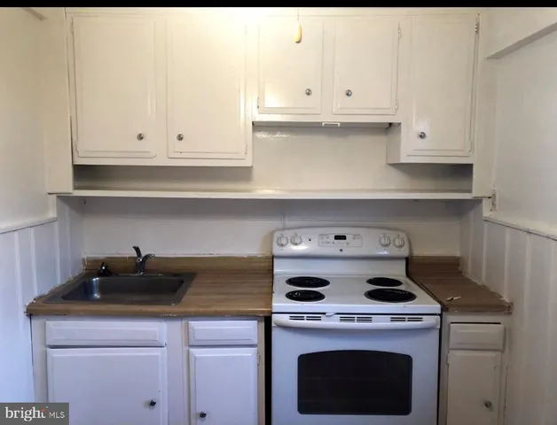 a kitchen with granite countertop white cabinets and white stove