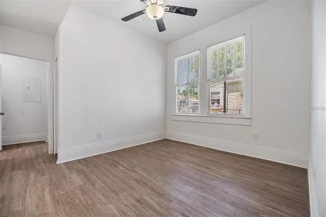 a view of an empty room with wooden floor and a window