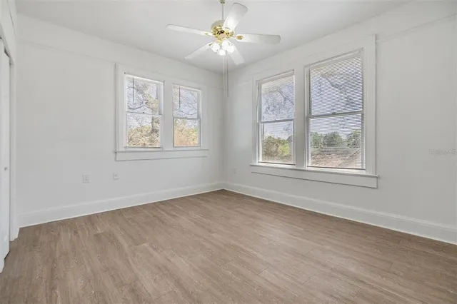 a view of an empty room with a window and wooden floor