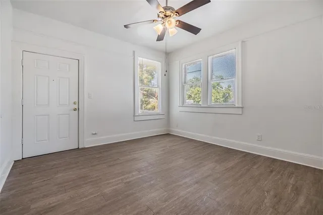 a view of an empty room with a window and wooden floor