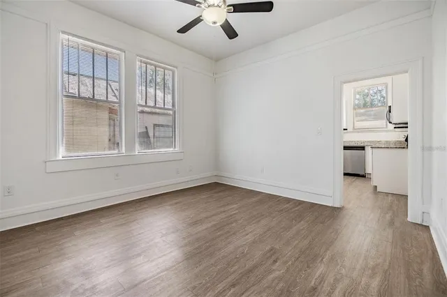 a view of an empty room with a window and wooden floor