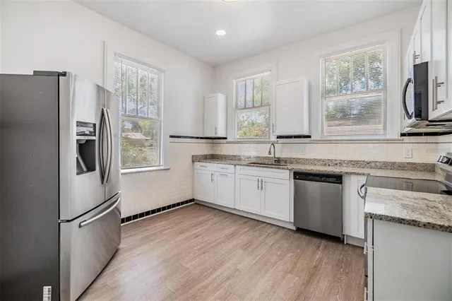 a kitchen with granite countertop a refrigerator a sink stainless steel appliances and cabinets