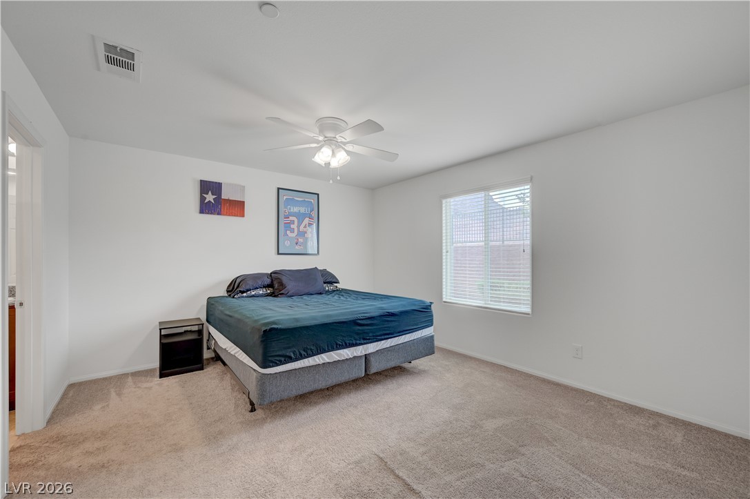 1287 Raritan Place Henderson, NV 89002 - Photo 3 of 21 A spacious bedroom with plush carpet and a wide window, offering a restful retreat.