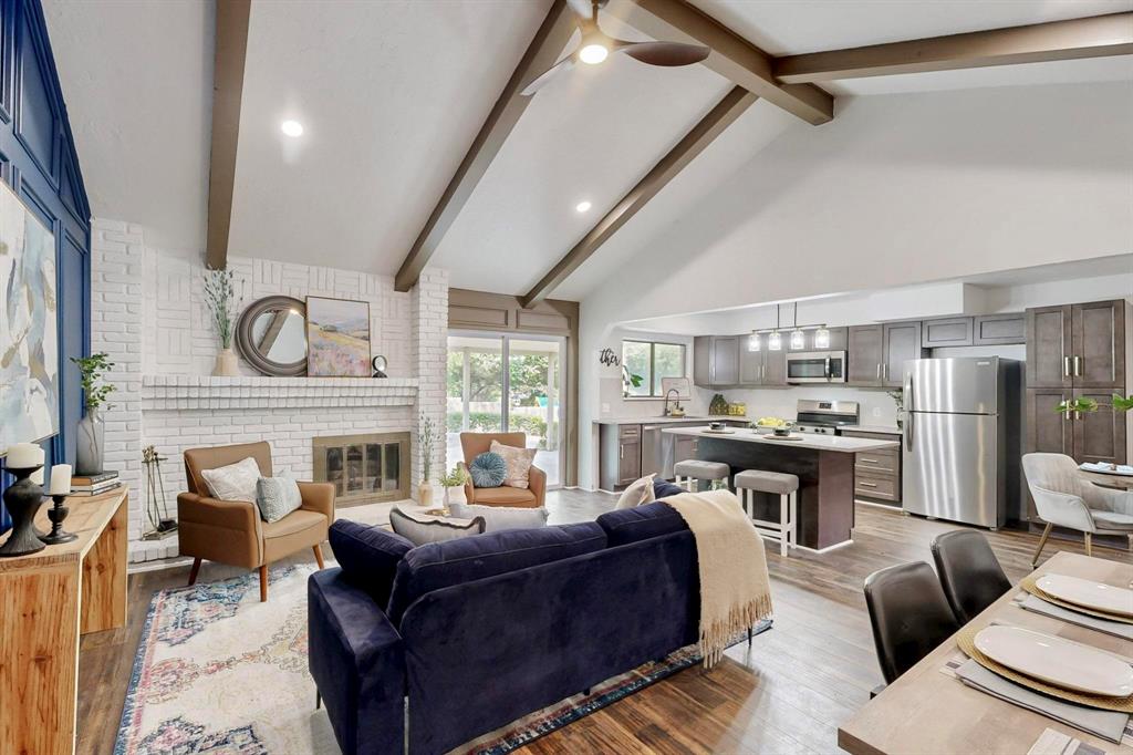 3965 Singleleaf Lane Fort Worth, TX 76133 - Photo 5 of 39 Vaulted ceilings with exposed beams, a white-painted brick fireplace, and wood-finish flooring define this open-concept living space