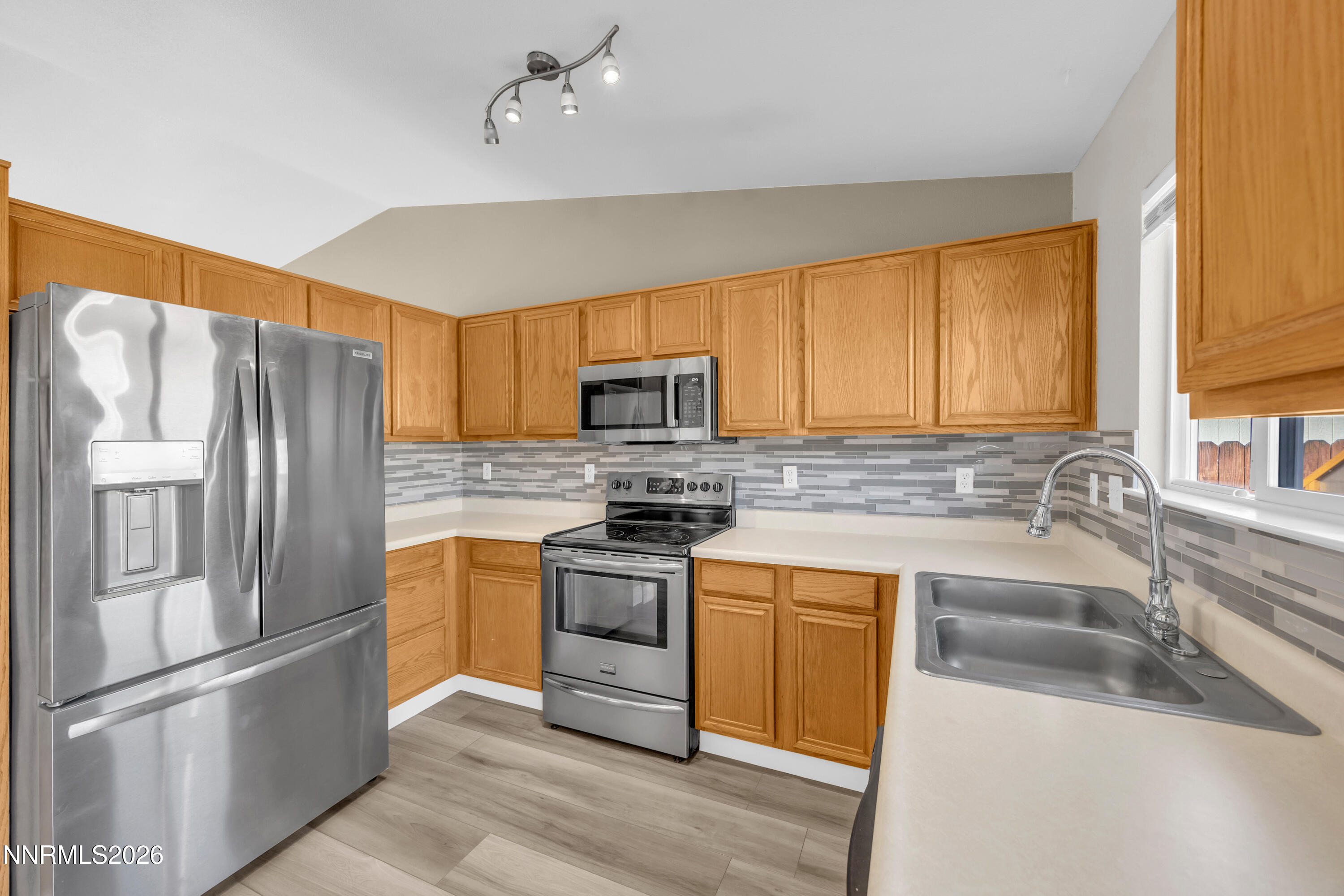 7295 Raphael Drive Sun Valley, NV 89433 - Photo 26 of 44 a kitchen with stainless steel appliances granite countertop a refrigerator a sink dishwasher a stove with wooden cabinets and floor