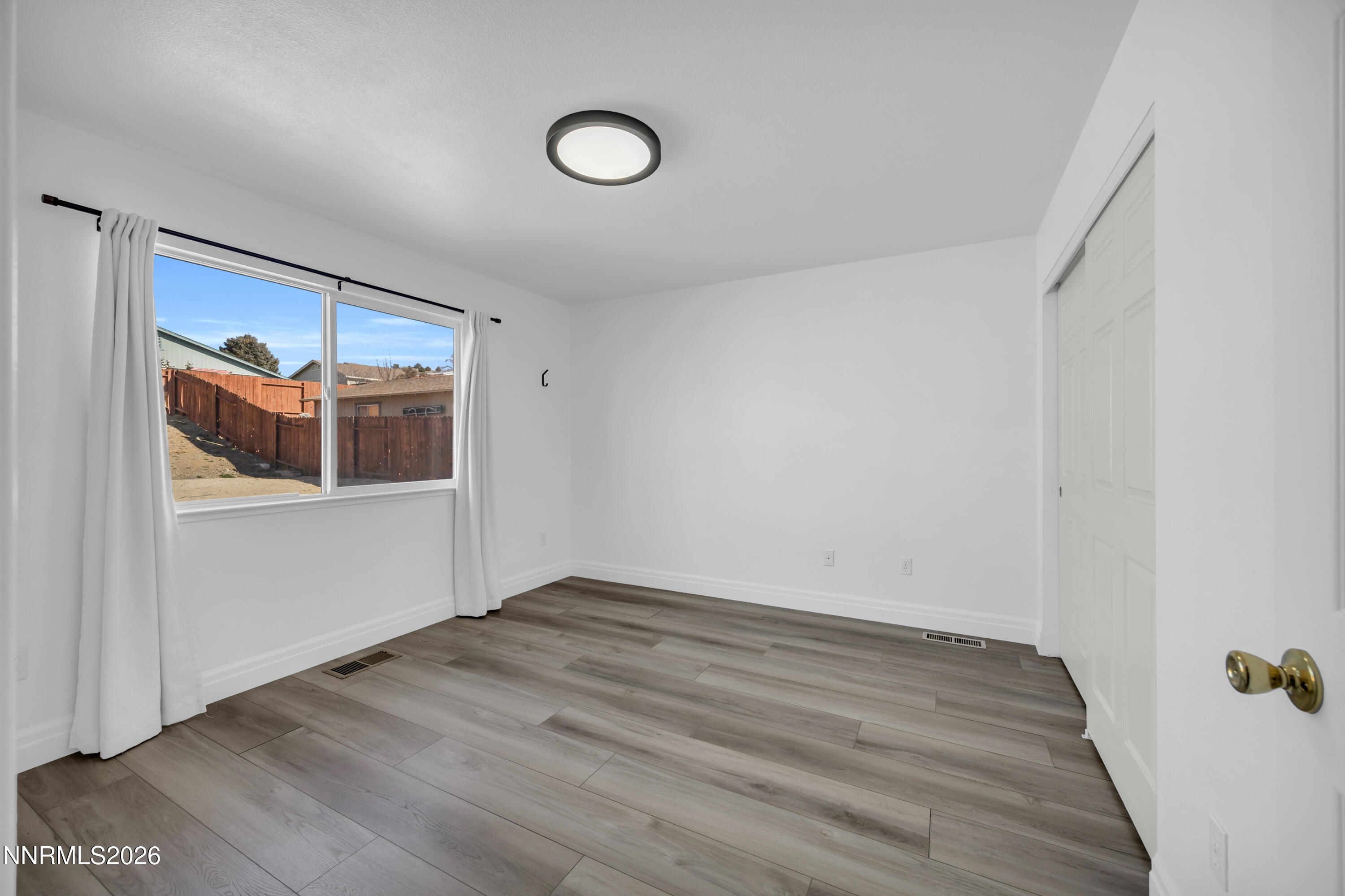 7295 Raphael Drive Sun Valley, NV 89433 - Photo 29 of 44 a view of an empty room with wooden floor and a window