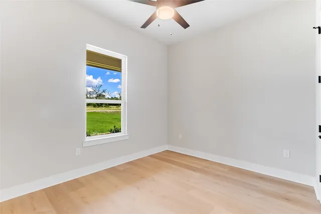 an empty room with a window and a ceiling fan